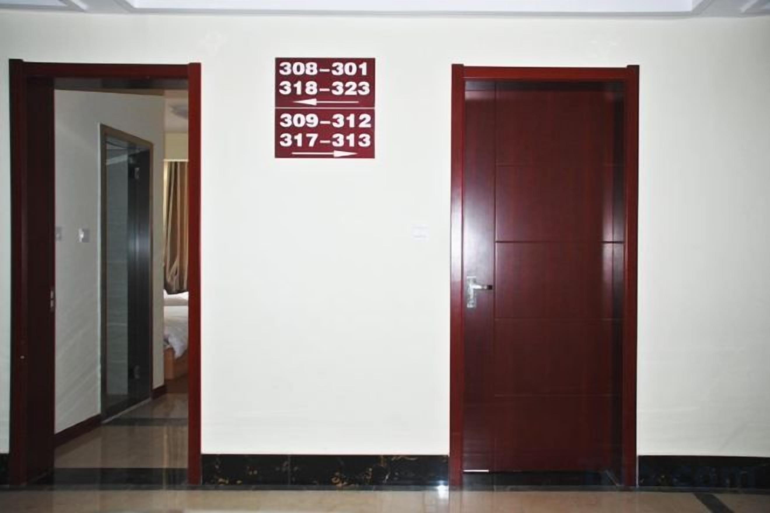 A hallway with a door and a sign listing room numbers 308-301, 318-323, 309-312, 317-313.