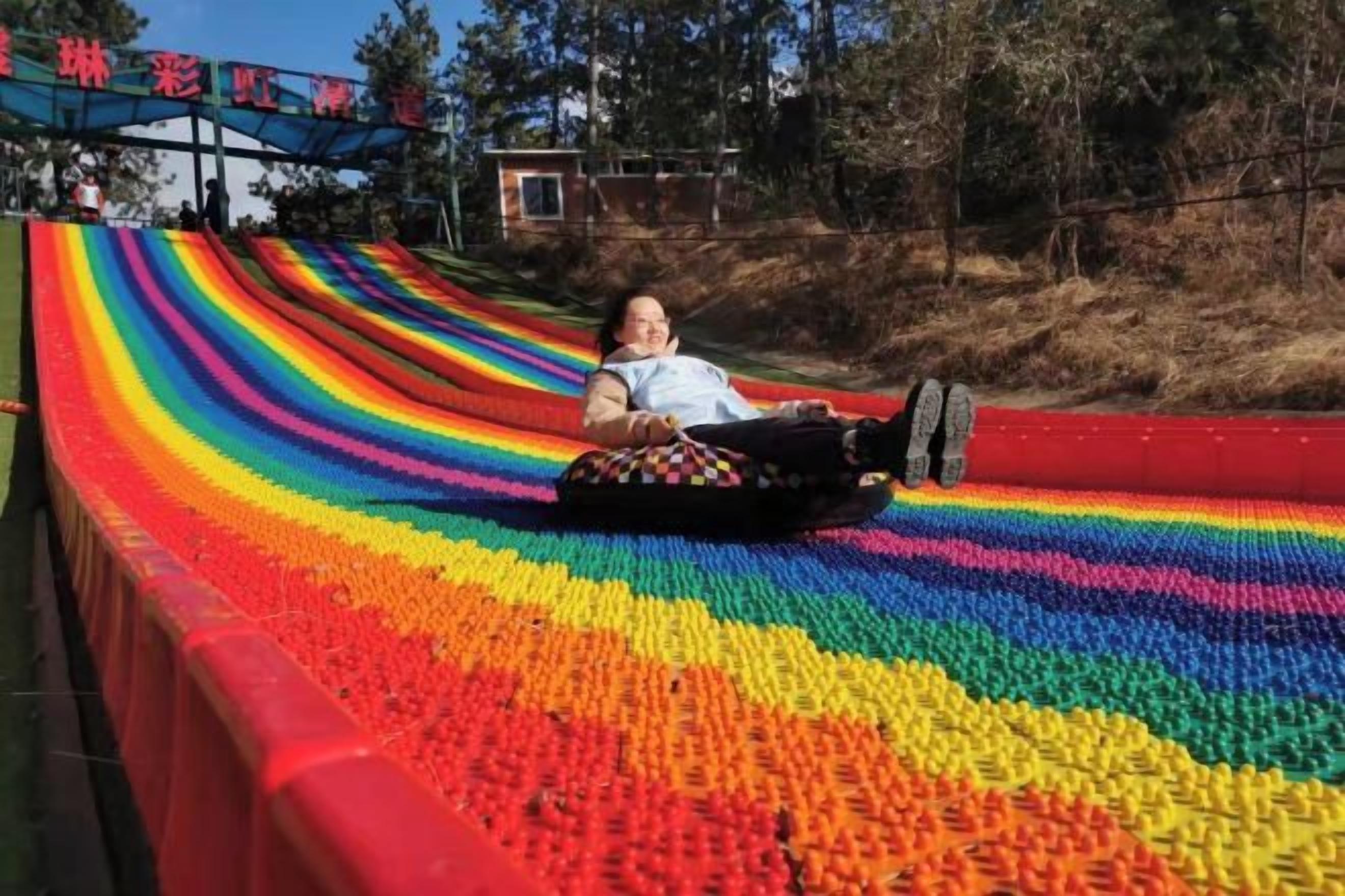 A person sliding down a rainbow-colored slide.