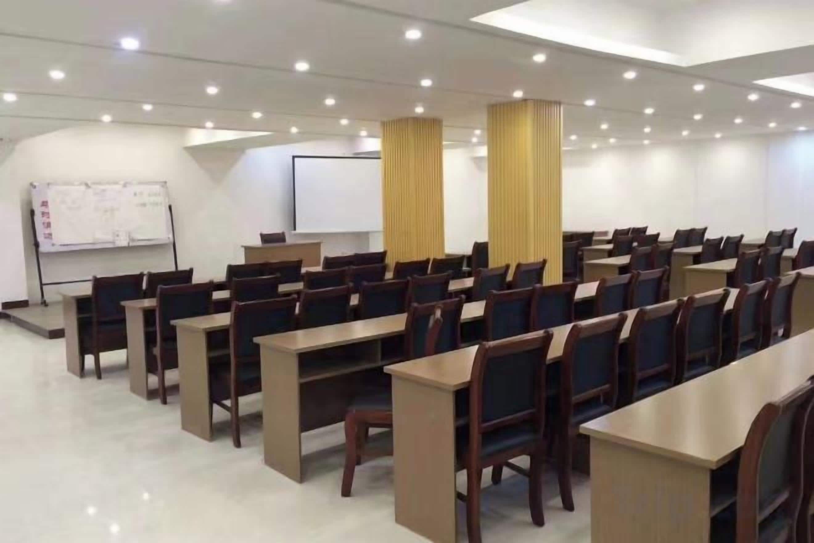 Ein Konferenzraum mit Tischen, Stühlen, einer Tafel und einer Projektionsleinwand.