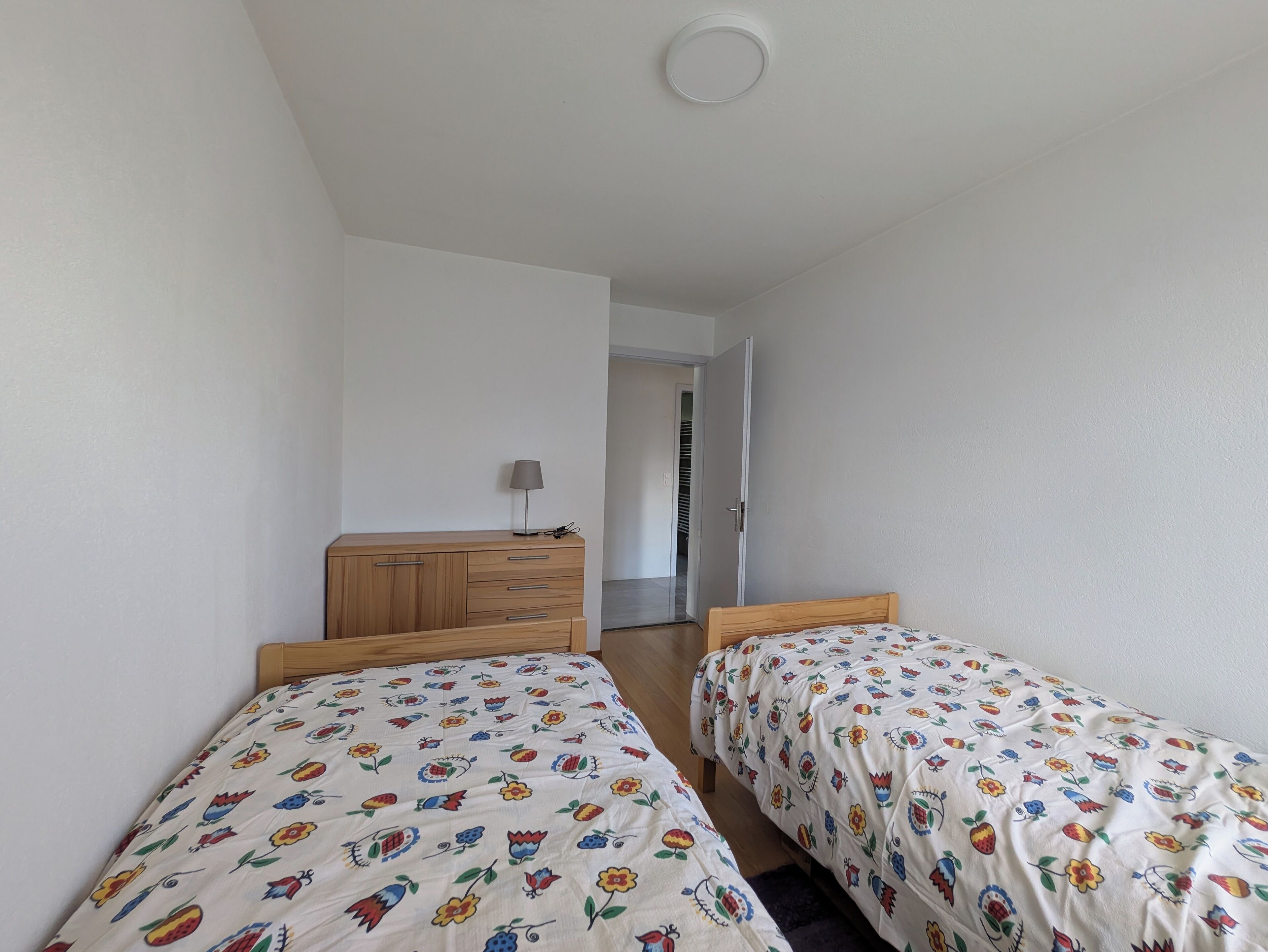 Un dormitorio con dos camas, un aparador de madera y una puerta que da a otra habitación.
