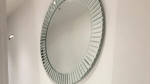 Un meuble-lavabo moderne et minimaliste, doté d’un miroir rond et d’un élégant plan-vasque métallique.