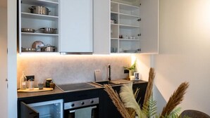 A modern kitchen with white cabinetry, a built-in oven, and a countertop with a kettle and a plant. - Stay at Brussels (Brussels)