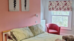 Un dormitorio con cama, una silla y obras de arte en la pared.