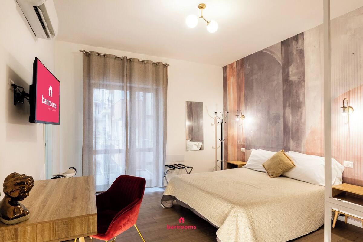 Una habitación de hotel con cama, escritorio, silla, televisión y vistas a la ciudad.