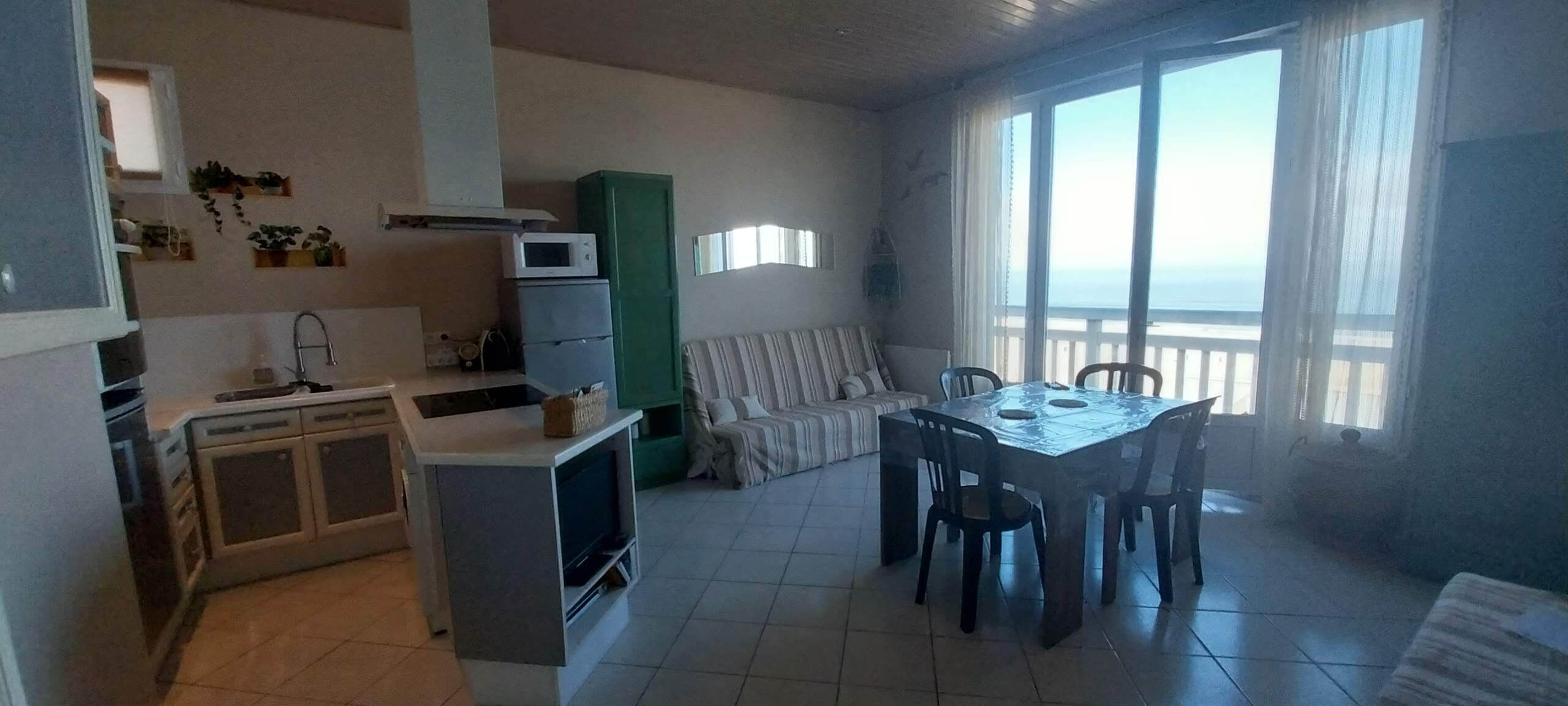 Un espacio habitable compacto con kitchenette, zona de comedor y sofá.