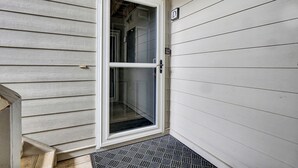 Una porta bianca con un pannello di vetro, un tappetino d'ingresso e una cassetta delle lettere a parete.