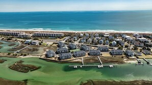 Vista aerea di una zona residenziale costiera con diversi edifici, un porto turistico e una spiaggia.