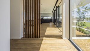 Ein modernes Interieur mit Holzboden, einer Glastrennwand und Blick ins Freie.