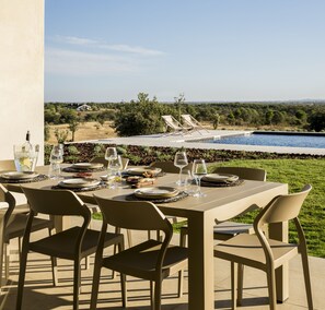 An outdoor dining area with a table set for four, overlooking a swimming pool and a scenic landscape. - Blissfully Alentejo by Cadenzalux (Mourão)