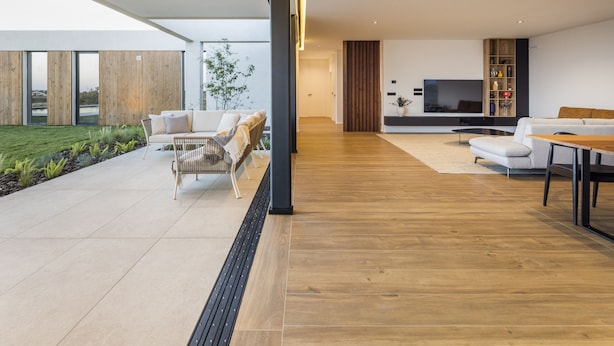 Ein modernes Wohnzimmer mit großem Fernseher, Holzboden und Blick ins Freie.