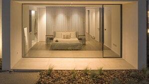 Ein modernes, minimalistisches Schlafzimmer mit einem großen Bett, einem Nachttisch und einem Beistelltisch.