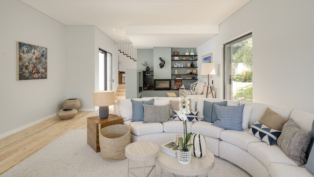 A modern living room with a curved sofa, a coffee table, and a staircase leading to an upper level.