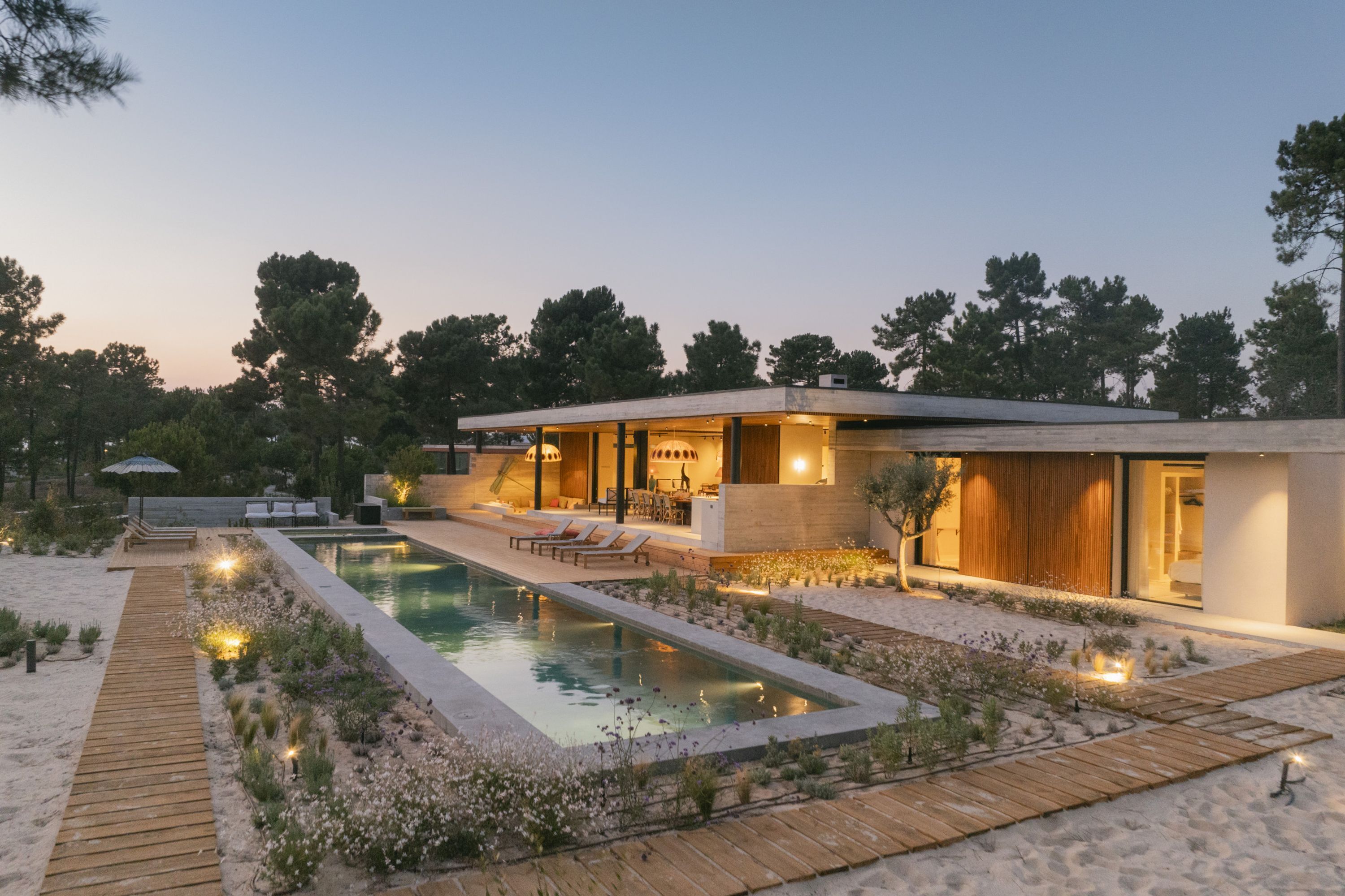 A modern house with a swimming pool, wooden deck, and outdoor seating area.