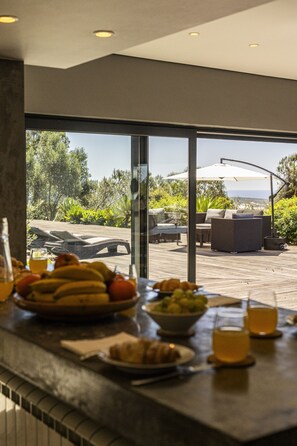 A breakfast setup with a view of an outdoor seating area and a pool. - Carmim Villa by Cadenzalux (Cascais)