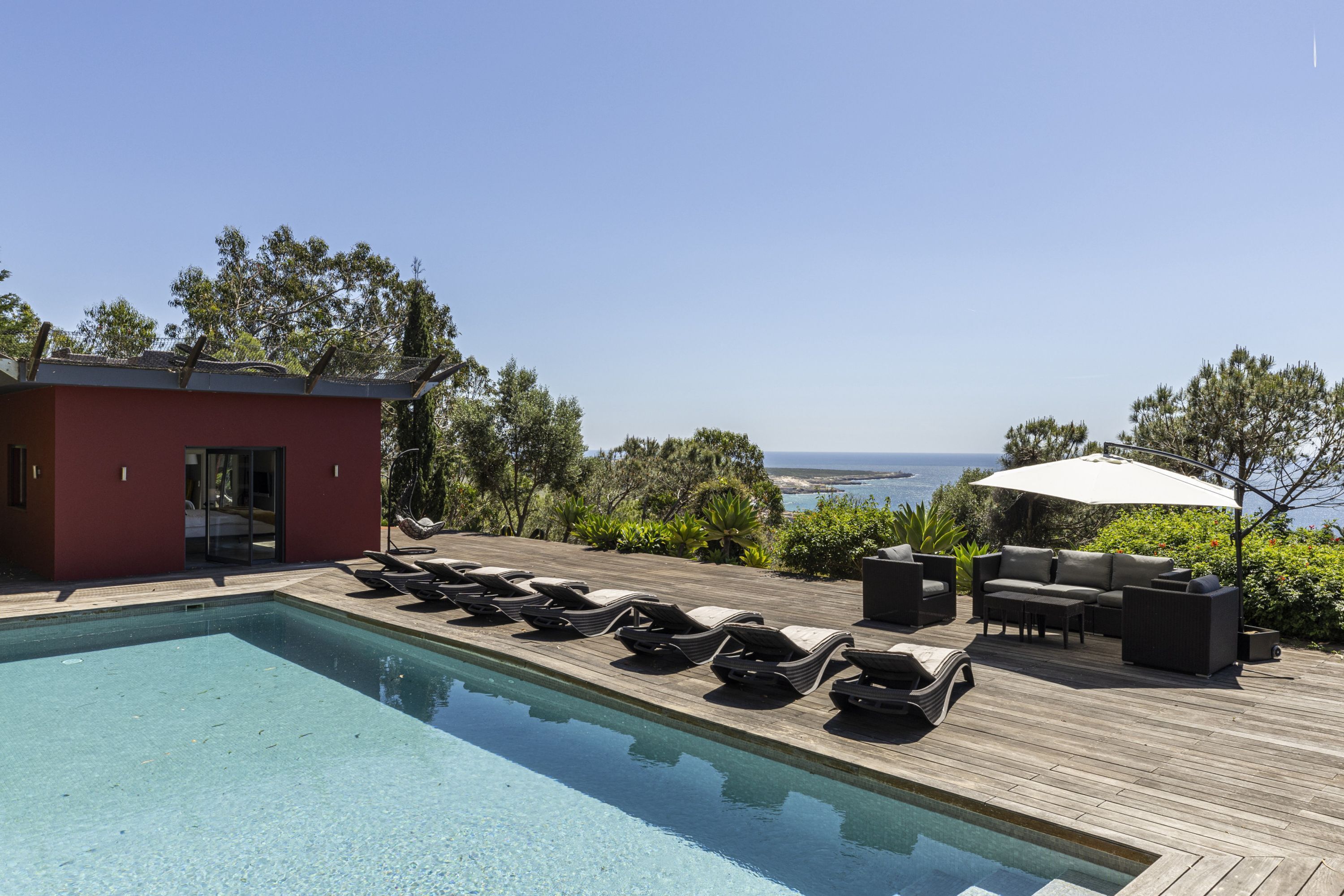 Ein Poolbereich mit Liegestühlen und einer Holzterrasse mit Blick auf eine schöne Aussicht.