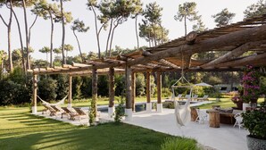 Un espacio al aire libre cubierto con sillones, una hamaca y una piscina.