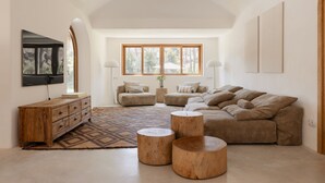 Un salón amplio con un gran ventanal, una mesa de centro de madera, un sofá y un aparador de madera.