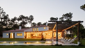 Una casa moderna con piscina, mobiliario exterior y una hamaca.