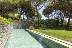 A swimming pool with stone walls and a grassy area with trees. - Havenwood Villa by Cadenzalux (Cascais)