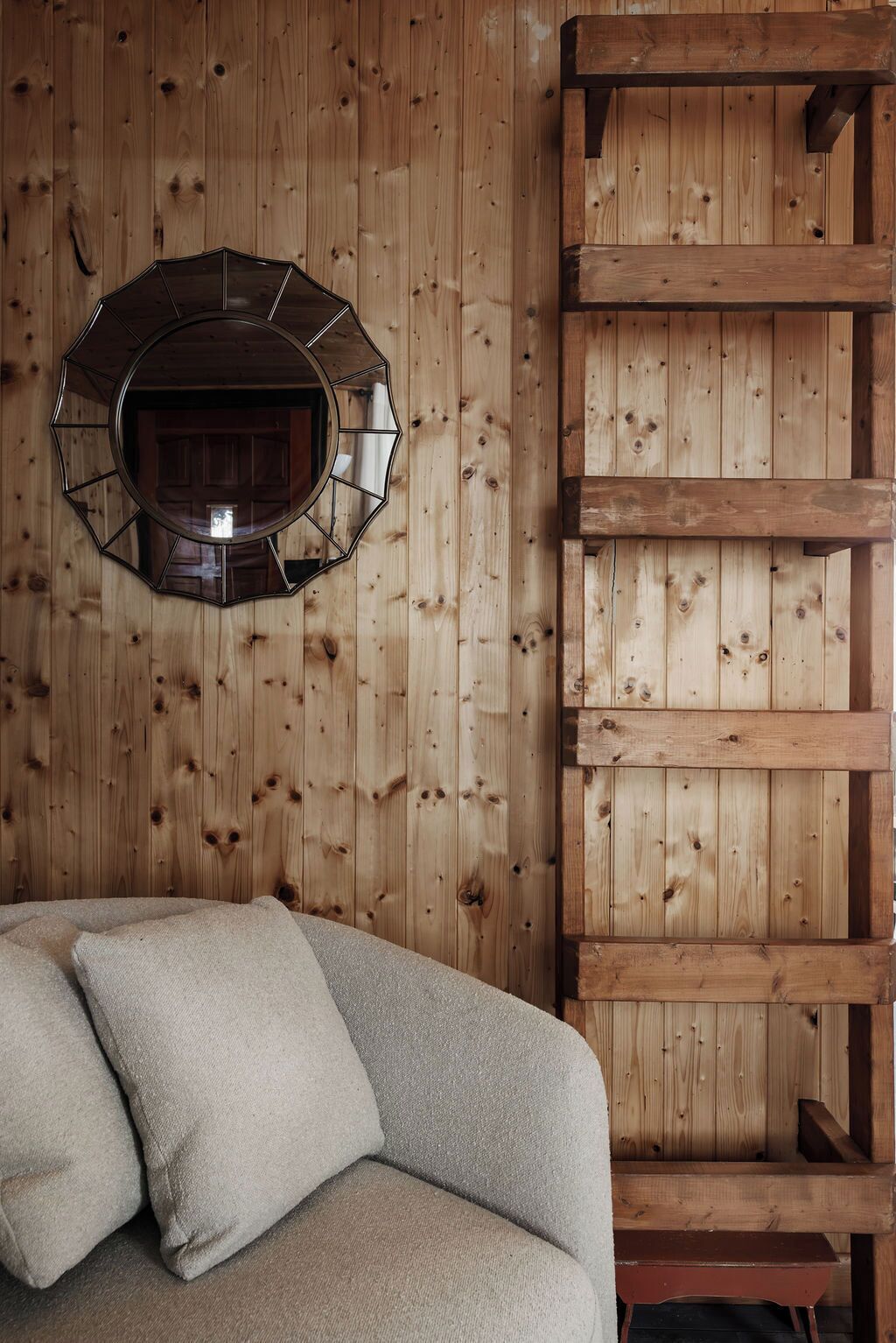 A wooden wall with a hexagonal mirror and a wooden bench.
