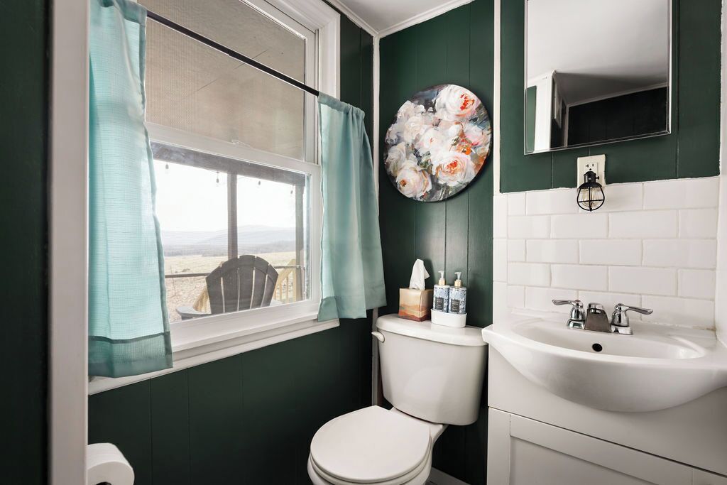 Ein Badezimmer mit Toilette, Waschbecken und einem Fenster mit Blick.