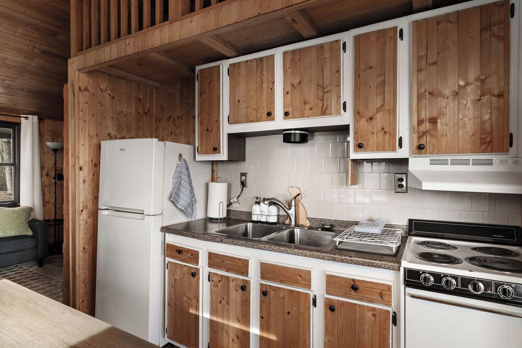 Una cocina con armarios de madera, un refrigerador blanco, una estufa y un lavaplatos.