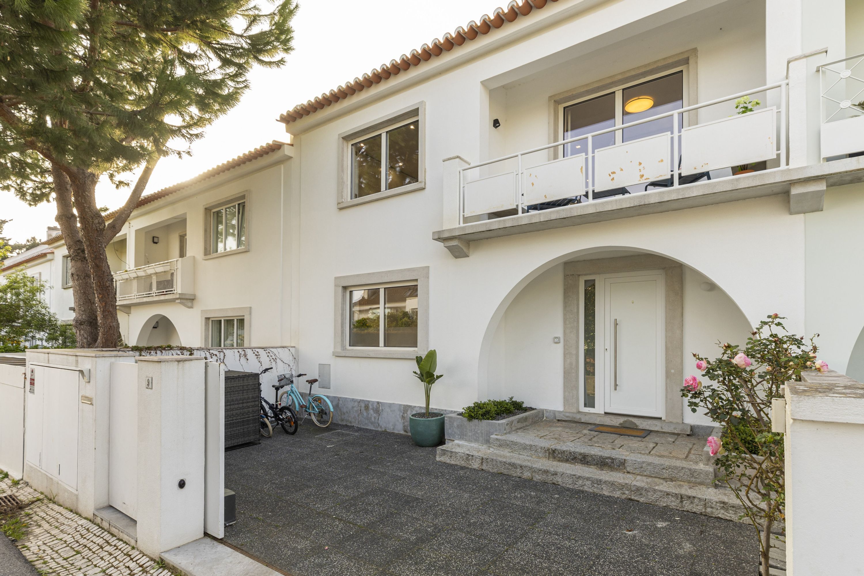 A two-story building with a white facade, a balcony on the upper floor, and a bicycle parked outside.