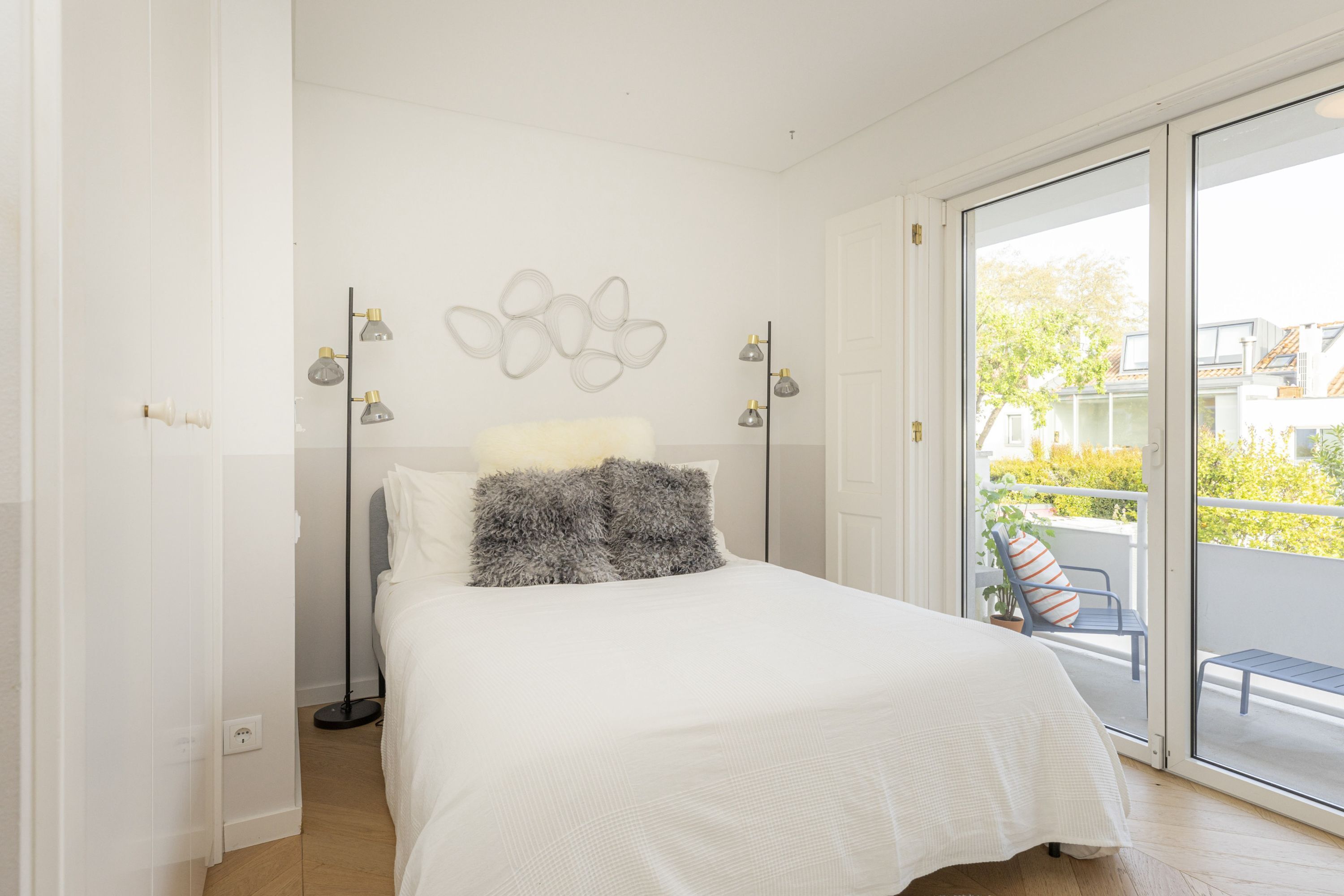 Une chambre avec un lit, une table de chevet, une lampe et une vue sur le balcon extérieur.