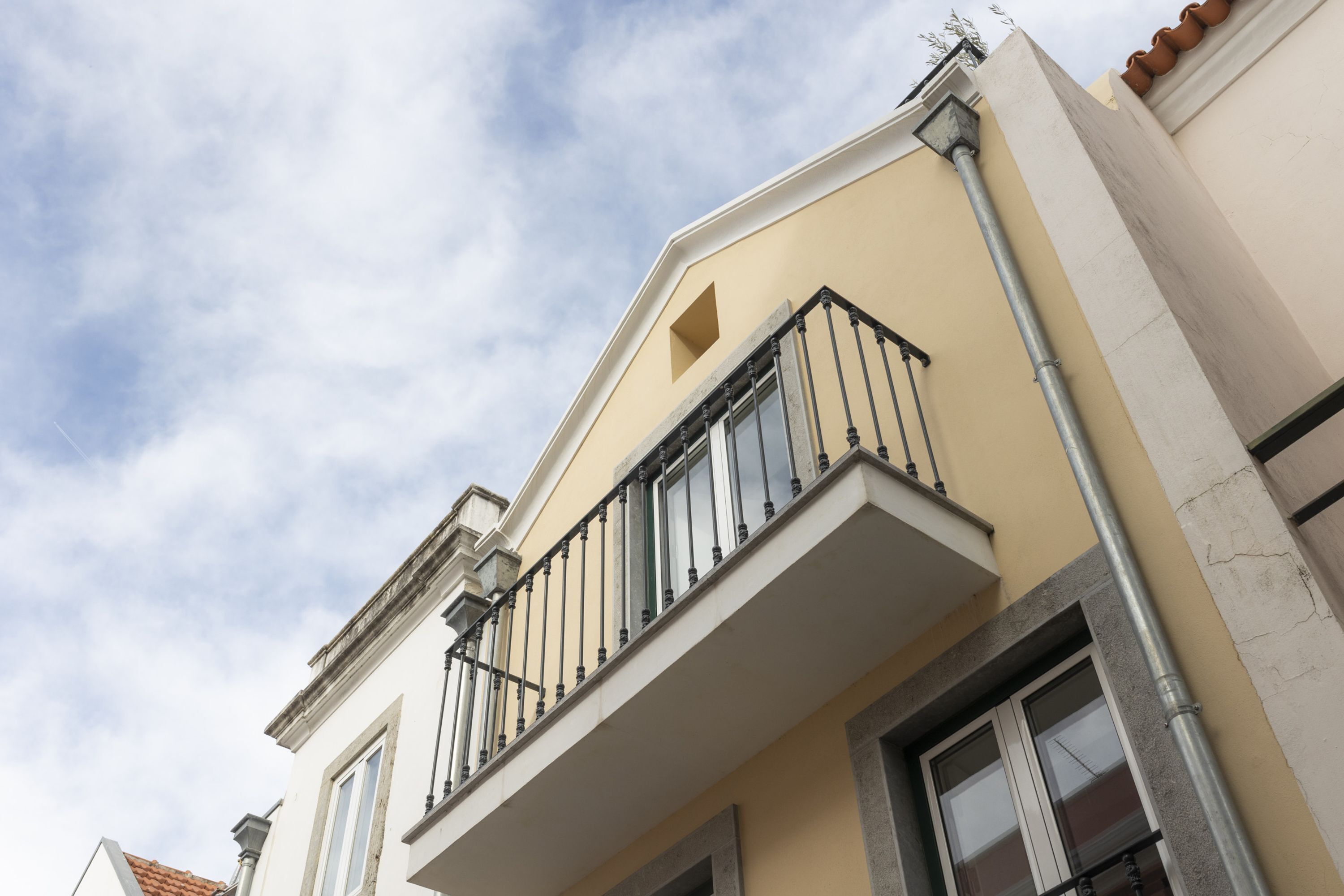 A building with a balcony, a window, and a visible pipe.