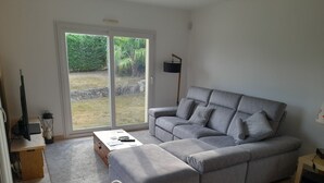 Ein Wohnzimmer mit einer grauen Eckcouch, einem Couchtisch, einem Fernseher und einem Hund.