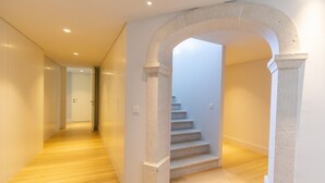 A hallway with wooden flooring, a stone archway, and a staircase leading to an upper level. - Chiado Rooftop Apartment by Cadenzalux (Lisbon)