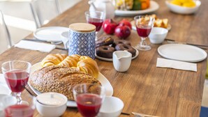 A dining table set with plates, cutlery, a loaf of bread, a pitcher, and glasses of red drink. - Chiado Rooftop Apartment by Cadenzalux (Lisbon)