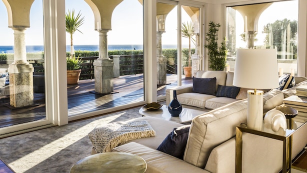 Un salon spacieux avec vue sur la mer, comprenant un canapé, une table basse et une lampe.