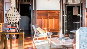 Un salon avec un canapé moderne, une table basse et une lampe. On aperçoit, au fond, un meuble en bois et une porte.