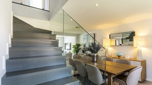 Un interior moderno con una escalera, zona de comedor y un espejo grande.