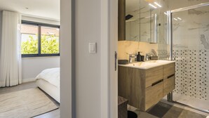 Un baño moderno con lavamanos de mármol, tocador de madera y cabina de ducha de vidrio.
