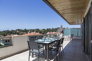 Un balcon avec une table dressée pour quatre personnes, des chaises et un plafond en bois.