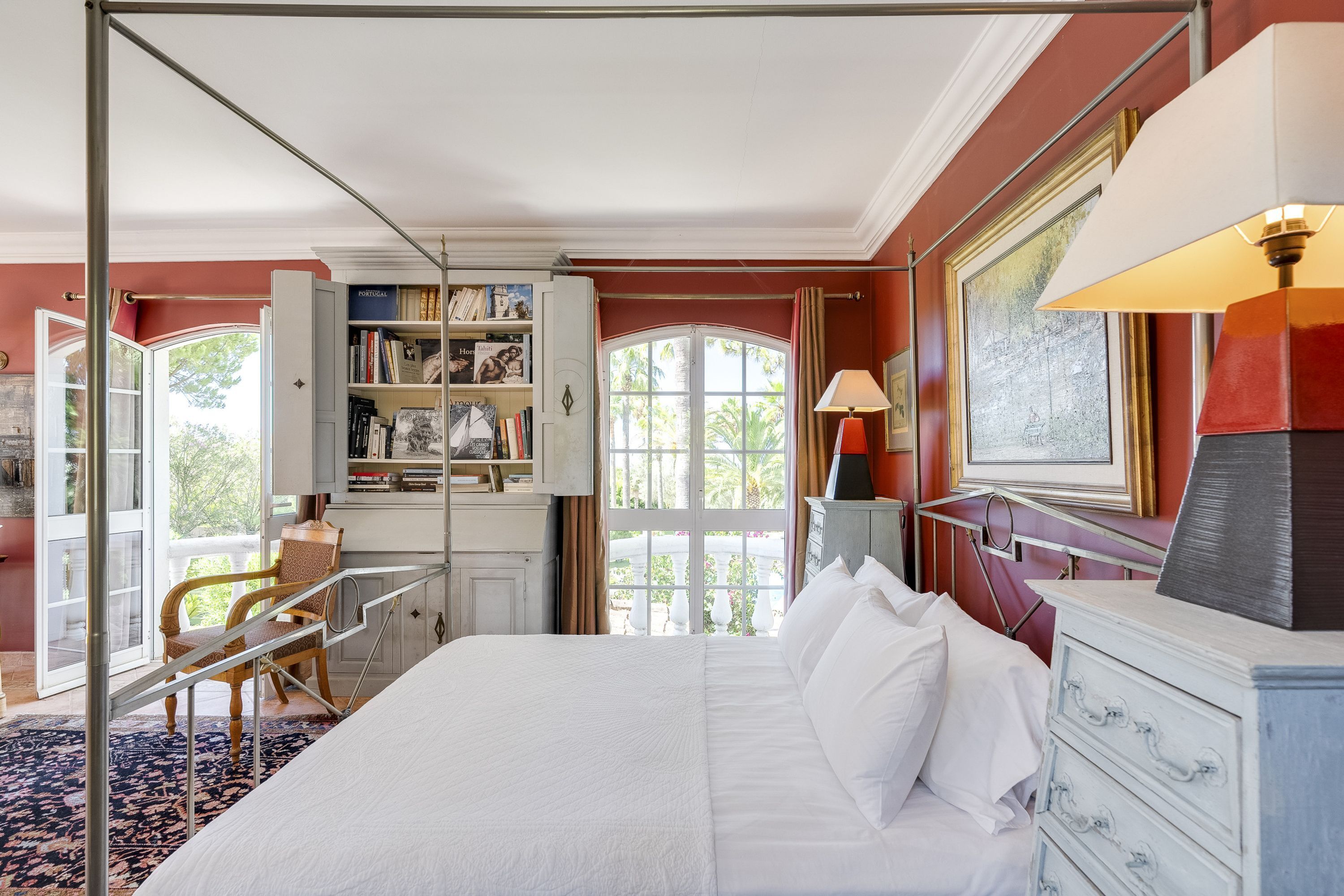 A spacious bedroom with a large bed, a wardrobe, a desk, and a view of the outdoors.