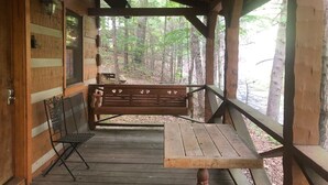 Een houten hut met een veranda, een bank en een tafel.