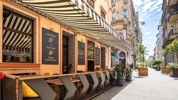 An outdoor seating area of a restaurant with a sign indicating it is lactose and gluten-free. - Dessewffy Premium Apartment (Budapest)