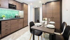 A modern kitchen with wooden cabinets, a microwave, and a green herringbone backsplash. - Dessewffy Premium Apartment (Budapest)