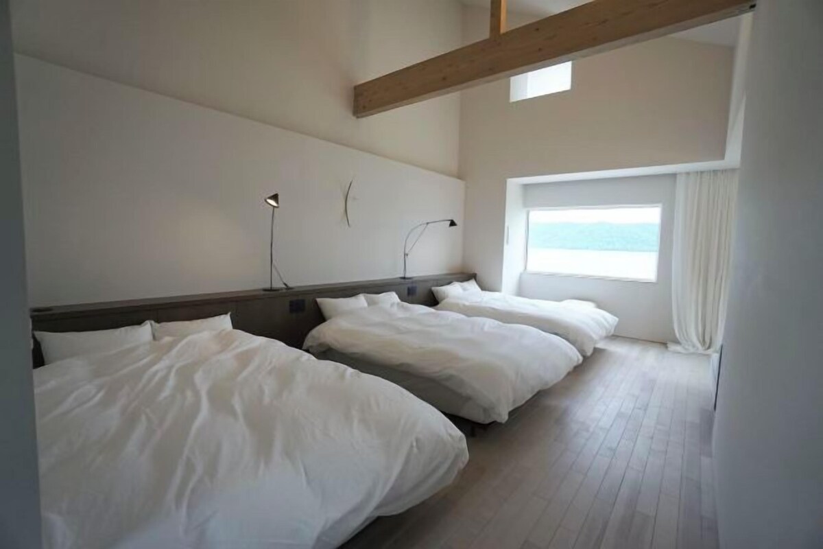 Ein Schlafzimmer mit zwei Betten, einem großen Fenster und einem Holzbalken an der Decke.