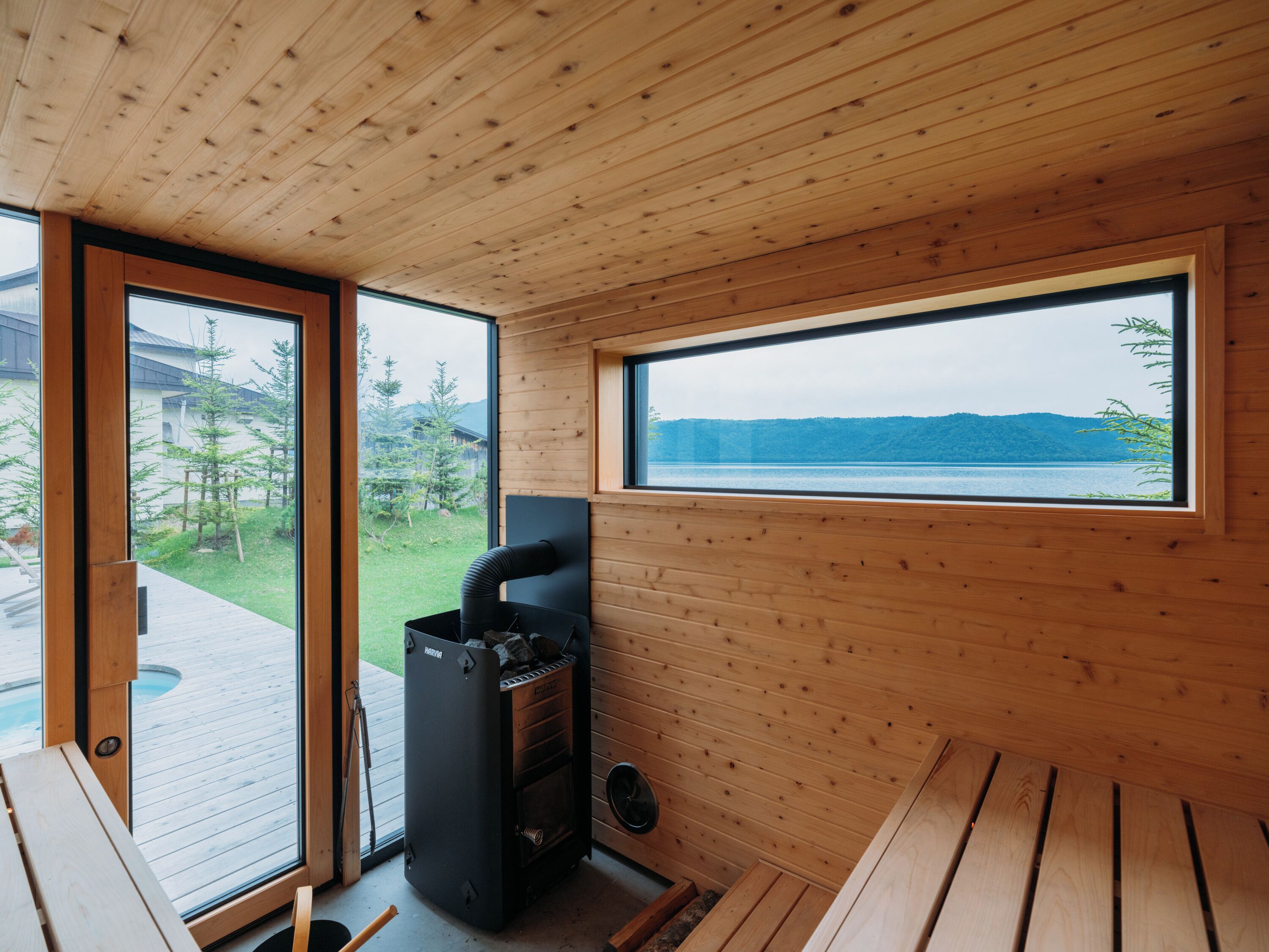 Una cabaña de madera con sauna, ventanas amplias y vista al lago.