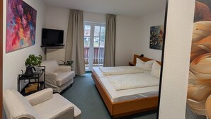 Une chambre d’hôtel avec un lit, un canapé, une télévision et des œuvres d’art accrochées aux murs.