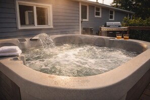Een jacuzzi met spetters, een handdoek en twee glaasjes op een tafel voor een huis.