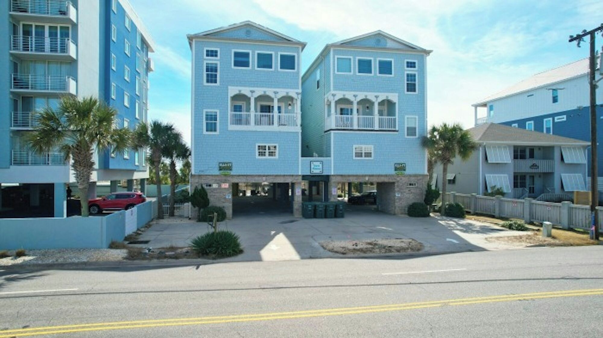 A two-story building with a central entrance, a parking area, and a red car parked in front.