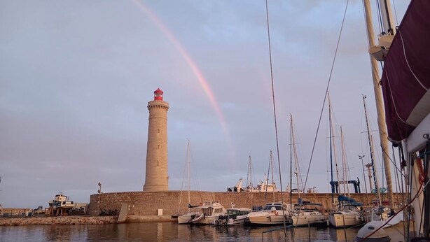 Un phare avec des bateaux amarrés au premier plan.