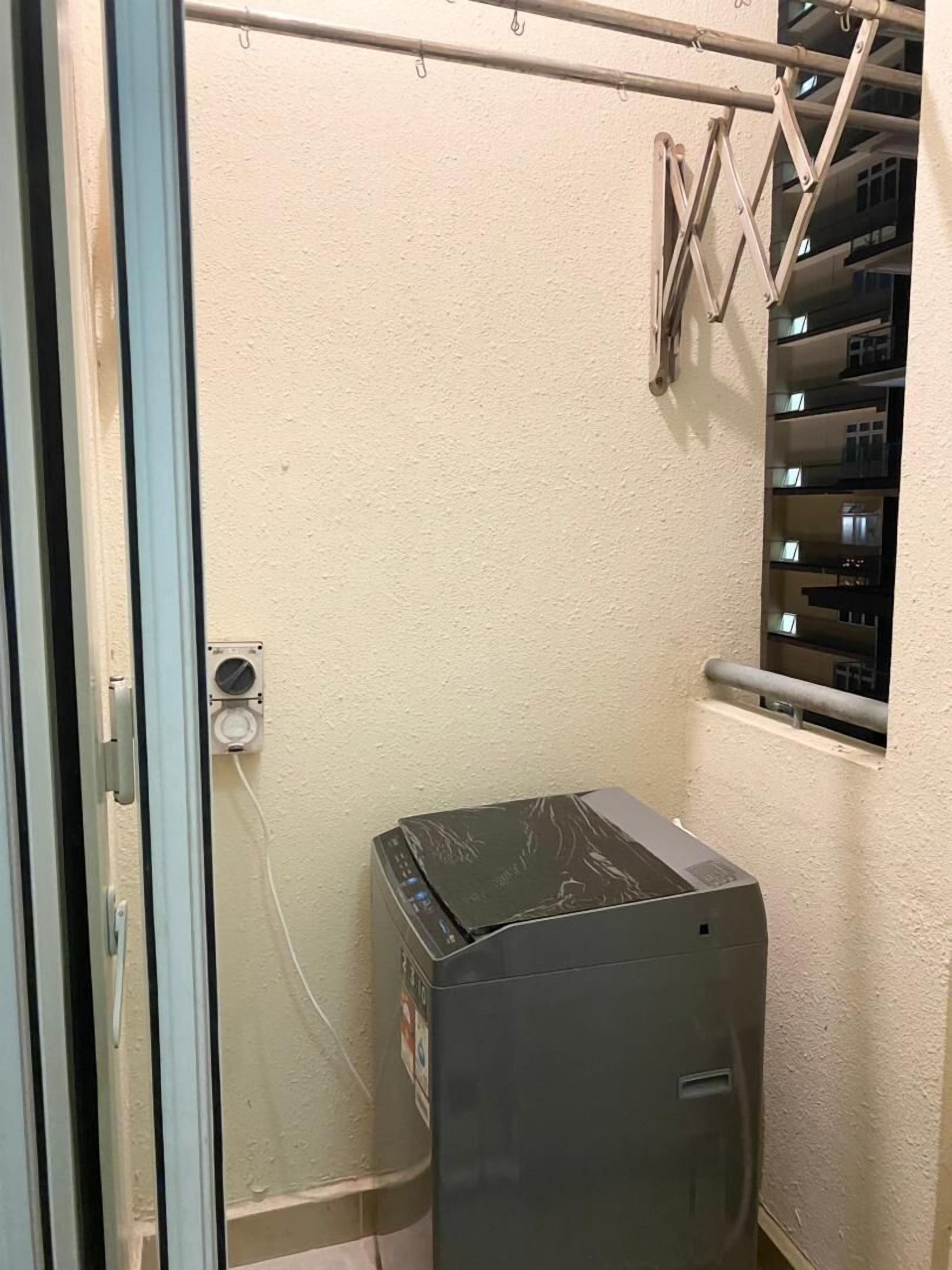 A compact room with a sliding door, a small window with a metal grill, and a wall-mounted air conditioning unit.