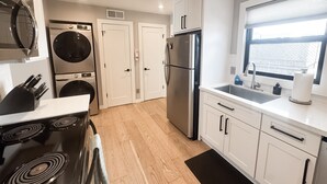 A modern kitchen with a stove, oven, microwave, washing machine, and refrigerator.