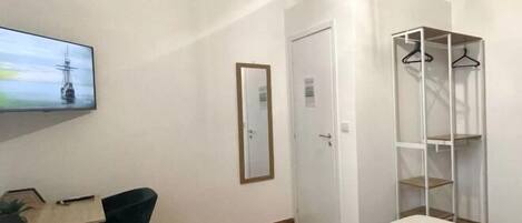 A bedroom with a bed, a TV, a wardrobe, and a desk with a chair.